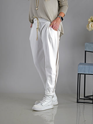 Person trägt die OFF#DLY Hose Mirella offwhite, eine sportliche Joggpant mit Gummibund, Kordelzug und seitlichen Taschen. Sichtbare weiße Stiefel ergänzen den Look.