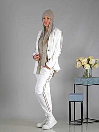 Eine Frau trägt den OFF#DLY Blazer Mariana in Offwhite, ein sportlicher Zweiknopf-Blazer mit seitlichen Streifen an den Armen, ohne Futter und angedeuteten Taschen.