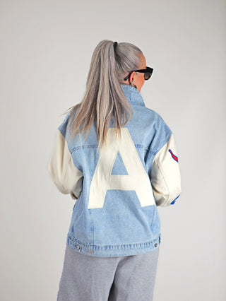 ALIX Mixed Sleeves Denim Jacket denimblue: Frau trägt eine oversized Denim-Variante mit gemischten Ärmeln und sportlichen Patches. Sichtbar sind Knopfleiste und große Rückenapplikation. Ideal für einen lässigen, modischen Look.