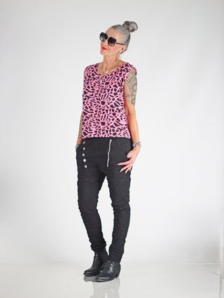 Eine Frau trägt die OFF#DLY Pant Celeste black, schmale Joggerpants mit Gummibund und Zugkordel, kombiniert mit schwarzen Stiefeln und einer pinken Bluse.