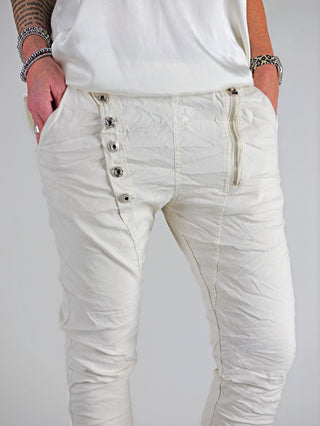 Produktbild der OFF#DLY Hose Celeste vanille: Eine schmale Joggerpant mit Gummibund, Zugkordel und sichtbaren Taschen vorne. Knopfleiste und Zipper ergänzen das Design.