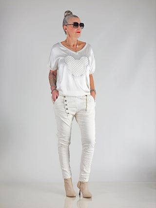 OFF#DLY Pant Celeste vanille, schmale Joggerhose mit Gummibund, Zugkordel und Taschen vorne und hinten, getragen von einer Frau in weißem Outfit, mit Sonnenbrille und Tattoos.