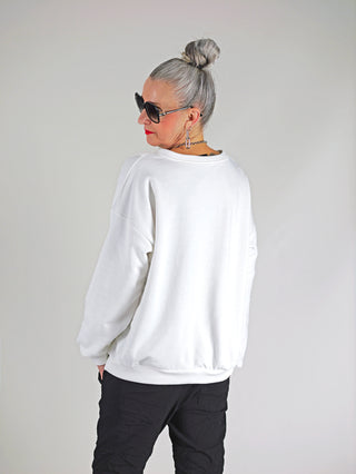 Frau trägt OFF#DLY Sweat Berry white, weißen Sweater mit „Berry Good Times“-Print. Locker geschnitten, rundhalsig, überschnittene Schultern, perfekt für einen lässigen, trendigen Look.