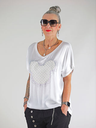 Frau trägt das OFF#DLY Shirt Maus white, ein elegantes T-Shirt mit Glitzer-Print und Materialmix, kombiniert mit Sonnenbrille und Halskette, für einen glamourösen Alltagslook.