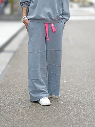 #VDR Pant grey: Person trägt stylische, weite graue Hose mit elastischem Bund und pinkem Kordelzug, kombiniert mit lässigem, modernem Look und markanten Nahtdetails. Perfekt für Streetstyle-Outfits.
