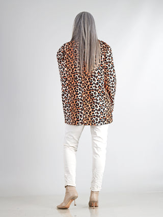Frau mit langen grauen Haaren trägt den Lumina Leo Blazer Oversized, ein auffälliger, lässig-eleganter Leopardenprint-Blazer, kombiniert mit weißen Hosen für einen stilvollen Look.