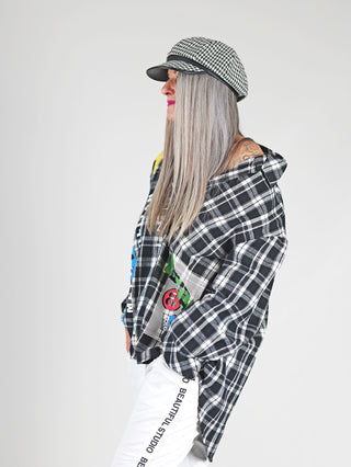 Off#DLY Shirt Canada black/white: Frau mit grauen Haaren trägt oversized karierte Hemdjacke aus 100% Baumwolle mit Print, langer Ärmel, Knopfleiste und Hut, verkörpert modernen Streetstyle.