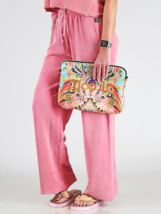 Dirty Laundry Towel Sweatpant Pomegranate: Person trägt pinke Joggpant mit elastischem Bund und weitem Schnitt, hält eine bunte Tasche. Perfekt für Komfort und Stil aus weicher Baumwolle.