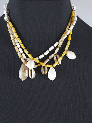 OFF#DLY Kette Mare multicolor aus Kunststoff und Polyester zeigt eine Halskette mit Muscheln und Steinen auf einem Mannequin, verziert mit einem auffälligen Muschelanhänger.