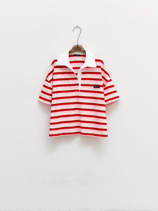 Lumina Polo Bluse pink/red: Ein gestreiftes, rot-weißes Poloshirt im Oversized-Look auf einem Kleiderbügel präsentiert, inspiriert von aktuellen Trends, ideal für einen lässigen, modischen Auftritt.