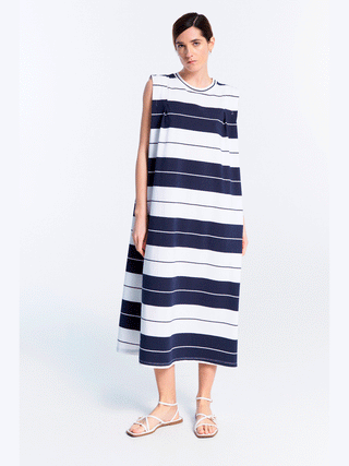 Frau in Lumina Dress Stripes blue, ärmelloses Maxikleid mit Streifenmuster, lockerer Schnitt, Rundhalsausschnitt, ideal für warme Tage.