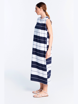 Frau in Lumina Dress Stripes blue, ärmelloses Maxikleid mit maritimen Streifenmuster, trägt Sandalen. Lockerer Schnitt umspielt Silhouette, ideal für sonnige Tage. Perfekt für entspannten, stilvollen Look.