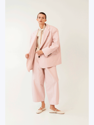 Frau trägt den Lumina Blazer rose, einen oversized Blazer mit Reverskragen und Ein-Knopf-Schließung, aus 100% Baumwolle. Perfekt für Business und Freizeit.