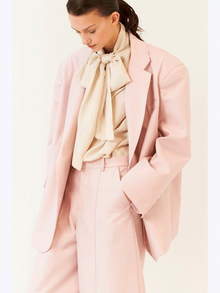Lumina Blazer rose: Frau in roséfarbenem Oversized-Blazer mit Reverskragen und Ein-Knopf-Schließung, zeigt lässigen Chic und moderne Eleganz. Perfekt für Business und Freizeitlooks.