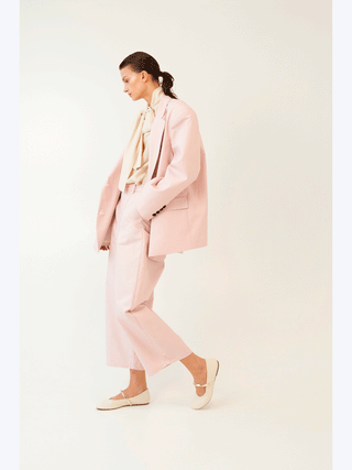 Frau in rosa Lumina Blazer, Oversized-Schnitt, klassischer Reverskragen, Ein-Knopf-Schließung, trägt weiße Schuhe. Der Blazer zeigt modernen Chic und lässige Eleganz.