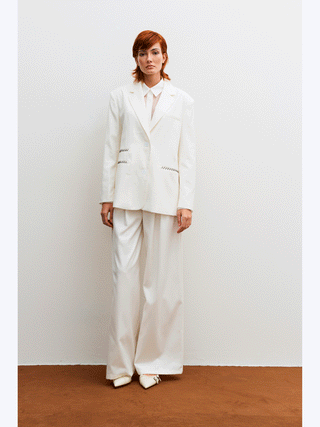 Lumina Blazer white: Frau trägt eleganten, leicht oversized Off-White-Blazer mit Reverskragen und Ein-Knopf-Schließung, kombiniert mit weißen Schuhen. Ideal für Business und Casual Outfits.