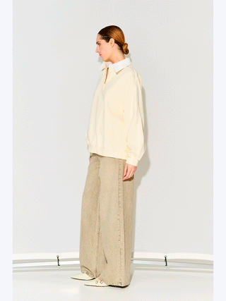 Lumina Sweat offwhite/crema: Oversized Baumwollsweater mit klassischem Polokragen und Knopfleiste, kombiniert mit weiten Jeans und spitzen, cremefarbenen Schuhen. Minimalistischer, eleganter Look, perfekt für vielseitige Outfits.