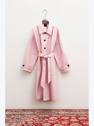 Lumina Mantel Rose: Ein eleganter Trenchcoat in Rosé mit markanten schwarzen Knöpfen und seitlicher Reißverschlusstasche, präsentiert auf einem Kleiderhaken. Perfekt für stilvolle, modebewusste Frauen.