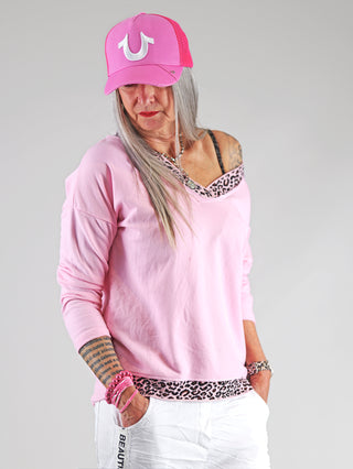 OFF#DLY Lightsweat Liora rose/leo: Frau trägt ein pinkfarbenes Sweatshirt mit auffälligen Leo-Details am Ausschnitt, kombiniert mit lässigem, sportlichem Stil für modebewusste Frauen.