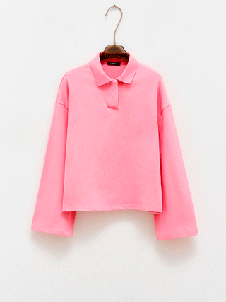 Lumina Polo Style Shirt pink auf einem Kleiderbügel, präsentiert in einem oversized, cropped Design mit klassischem Polokragen und verdeckter Knopfleiste, ideal für einen lässigen, modernen Look.