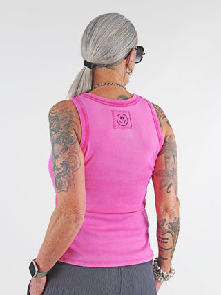 OFF#DLY Top Neve pink: Frau trägt lässiges Baumwoll-Tanktop mit Smiley-Patch auf dem Rücken, Tattoos sichtbar. Ideal für Sommer, vielseitig kombinierbar, sportlicher Rundhalsausschnitt, Einheitsgröße bis 40.
