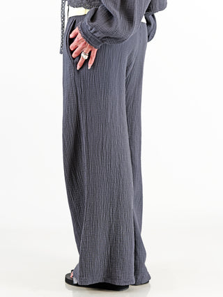 Frau trägt OFF#DLY Musselin Pant Frida anthrazit, luftige Wide-Leg-Hose mit elastischem Bund und Kordelzug, aus weicher Baumwolle, ideal für entspannte und stilvolle Outfits.