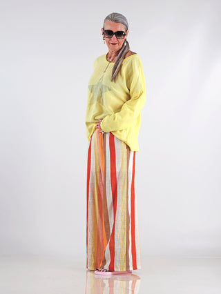 OFF#DLY Tee STAR yellow: Frau trägt gelbes Oversize-Shirt mit Stern-Print, kombiniert mit rot-weiß gestreiften Hosen. Das Shirt hat einen weiten Rundhalsausschnitt und verleiht einen lässigen, urbanen Look.