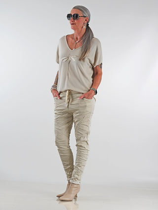 Eine Frau trägt die OFF#DLY Pant Stripes Gitta beige, eine beige Streifenhose mit elastischem Bund und schmal zulaufendem Bein, die lässig und stylisch wirkt.