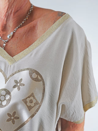 OFF#DLY Shirt Heart beige mit großem Herz-Print und goldenen Glitzer-Details, V-Ausschnitt mit Lurexkante, sichtbar auf einer Frau getragen, betont feminine Eleganz.