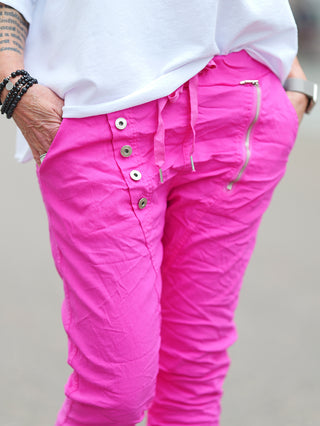 OFF#DLY Pant Celeste pink, getragen von einer Person, zeigt stilvolle, asymmetrische Knöpfe und dekorative Reißverschlüsse, passend für einen lässigen, modernen Look. Perfekt kombinierbar für Alltag und Freizeit.