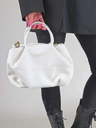 Frau hält die Enrico Coveri Tasche klein weiß mit abnehmbarem Perlenhenkel in der Hand, elegantes Design aus strukturiertem Kunstleder, perfekt für vielseitige Kombinationen.