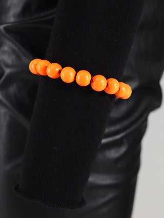 OFF#DLY Kugelarmband orange, getragen am Handgelenk. Es zeigt runde Holzperlen, die angenehm leicht wirken, perfekt für sommerliche Outfits oder als modisches Statement.