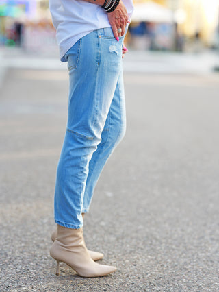 Jeans OFF#DLY Destroy Lightblue Denim Indira mit leicht vertieftem Schritt, Used-Effekten, getragen mit tanfarbenen Boots. Die Jeans hat dezente Destroyed-Details und einen modernen, lässigen Look.