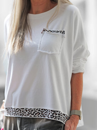Frau trägt OFF#DLY Boxy Sweat Alba white/leo, ein oversized Sweater mit Brusttasche und Leoparden-Details an Saum und Tasche, gefertigt aus Baumwoll-Polyester-Mix.