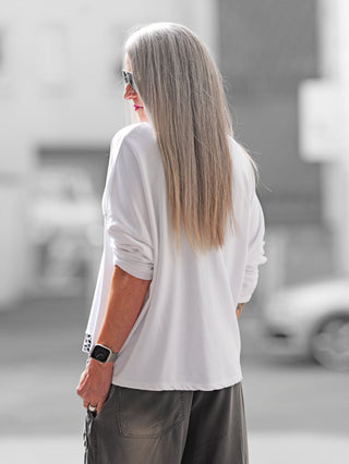 Frau trägt OFF#DLY Boxy Sweat Alba white/leo mit Oversize-Schnitt, Leo-Details an Saum und Brusttasche, kombiniert mit Sonnenbrille. Ideal für modische Alltagslooks.