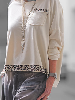Frau trägt den OFF#DLY Boxy Sweat Alba vanille/leo, einen oversized Sweater mit Leo-Details, Brusttasche und rundem Ausschnitt, ideal für trendige Alltagslooks.