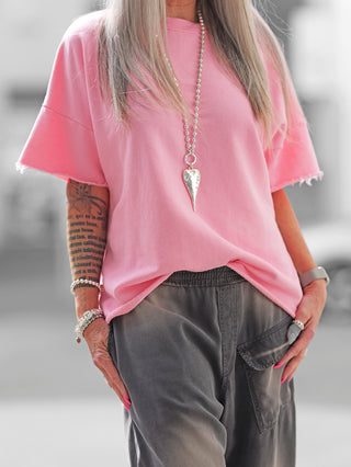 Frau trägt den OFF#DLY Sweat Lola rose, einen oversized Kurzarm-Sweater mit Raw-Edge-Saum, ideal für lässige Sommerlooks. Hergestellt in Italien, passend bis Größe 40/42.