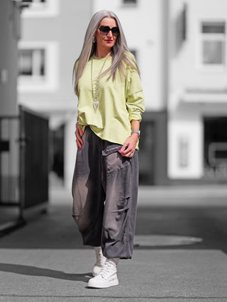 Frau trägt den OFF#DLY Lightsweat Calista pistazie, einen leichten, boxy geschnittenen Sweater mit Used-Look und offenen Kanten, ideal für Übergangswetter.