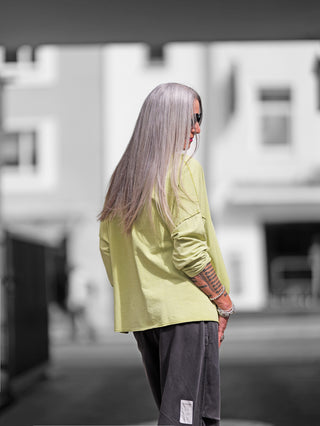 Person trägt den OFF#DLY Lightsweat Calista pistazie, einen legeren Boxy-Sweater mit Used-Look, langen Ärmeln und sichtbaren Nähten. Ideal für Übergangszeit, aus weicher Baumwolle gefertigt.