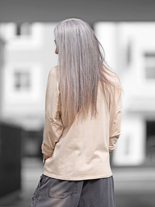 Frau mit langen grauen Haaren trägt das OFF#DLY Longsleeve Maelis beige, Oversize-Boxy-Schnitt, Rundhalsausschnitt, lange Ärmel. Perfekt kombinierbar für einen lässigen, vielseitigen Look.