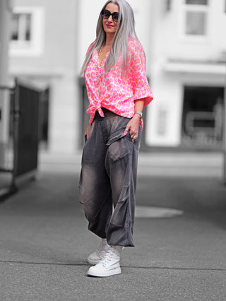 OFF#DLY Bluse Musselin Liora Leo pink: Frau trägt pinke Bluse mit Leo-Muster, weichem Musselinstoff, klassischem Kragen und Knopfleiste. Perfekt für sommerliche Outfits, lässiger Schnitt.