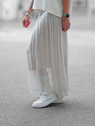 OFF#DLY Rock Sienna lightgrey: Eine Person trägt einen fließenden Maxirock mit weitem, weichem Bund und leicht gekräuseltem Stoff, kombiniert mit weißen Schuhen. Ideal für elegante und lässige Looks.