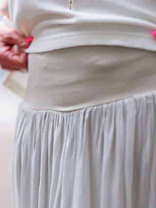 OFF#DLY Rock Sienna lightgrey: Person trägt eleganten Maxirock mit fließendem Schnitt und breitem Bund, ideal für feminine Silhouette. Perfekt kombinierbar und angenehm zu tragen.