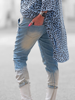 Person trägt OFF#DLY Boyfit Denim lightblue, lässige Jeans mit weiter Silhouette, kombiniert mit Leopardenmantel und weißen Stiefeln. Ein urbaner, moderner Look mit leichtem Used-Effekt.