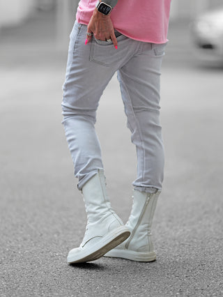 Person trägt OFF#DLY Destroy Denim Zelda lightgrey, eine lässige graue Jeans mit dezenten Destroyed-Elementen und unterlegtem Stoff, kombiniert mit weißen Stiefeln für einen urbanen Look.