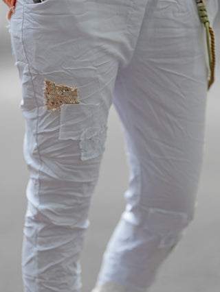 OFF#DLY Pant Vesper white, Nahaufnahme zeigt weiße Jogpant mit Paillettenpatches und dekorativer Kordel an Gürtelschlaufe, im Crinkle-Look, elastischer Bund, lässige Passform. Ideal für Frühling und Sommer.