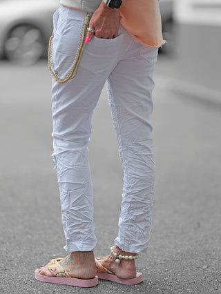 OFF#DLY Pant Vesper white: Jogpant mit Paillettenpatches, Crinkle-Look und dekorativer Kordel, getragen von Person in weißen Hosen, zeigt stilvolle Details und entspannte Passform, ideal für Frühling und Sommer.