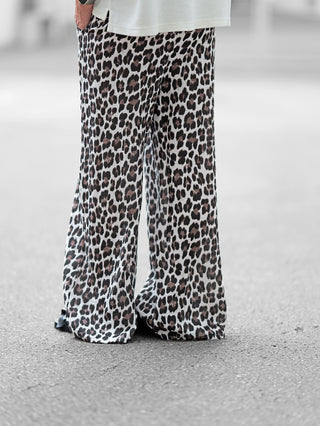 OFF#DLY Musselin Pant Leo black/white: Eine Person trägt luftige, weite Musselin-Hose mit Leopardenmuster, elastischem Bund und Kordelzug, ideal für entspannte Tage und stylische Outfits.