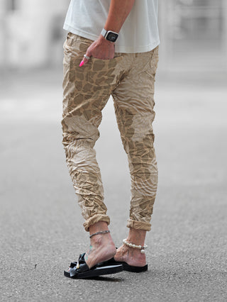 Person trägt OFF#DLY Print Pant Lindsey camel, edle Crinkle-Hose mit Silk-Touch. Komfortabler Schnitt, elastischer Bund, perfekt für entspannte Looks. Fokus auf die Hose, keine Farbe oder Hintergrunddetails.