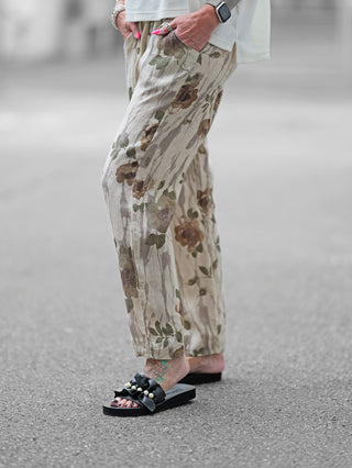 OFF#DLY Linen Pant Romy beige/khaki, weite Leinenhose mit floralem Muster und elastischem Bund, getragen mit Sandalen. Perfekt für einen sommerlichen, lässigen Look.